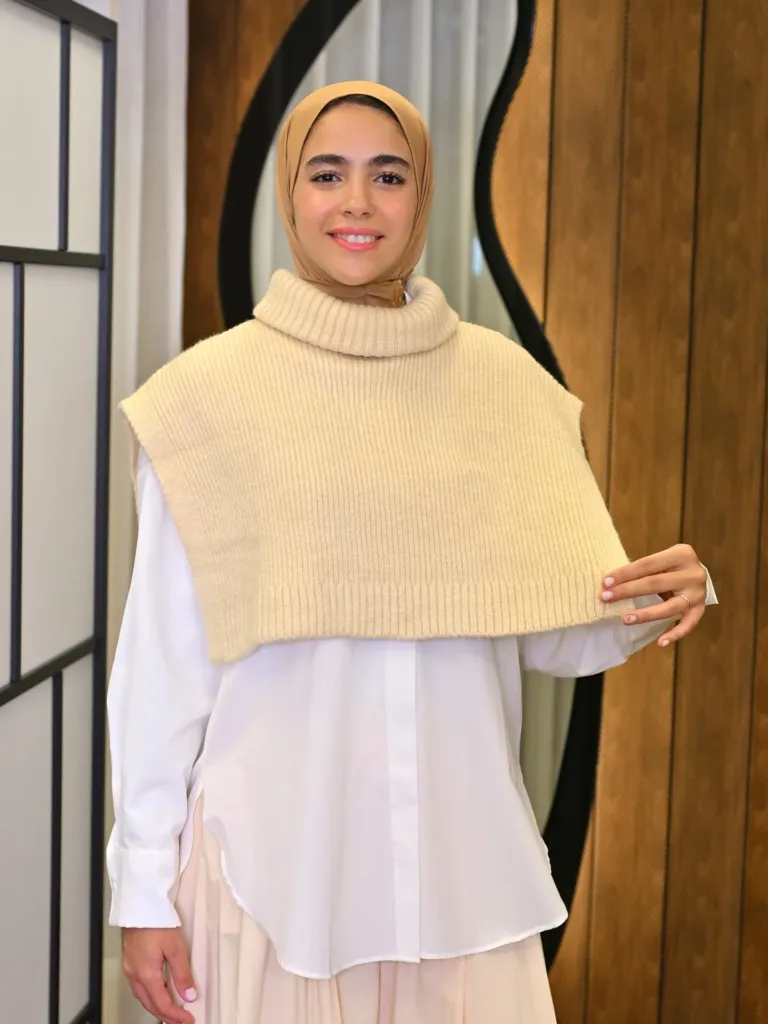 Alma Knit beige, tricot sans manches à col montant sur chemise blanche, porté avec hijab